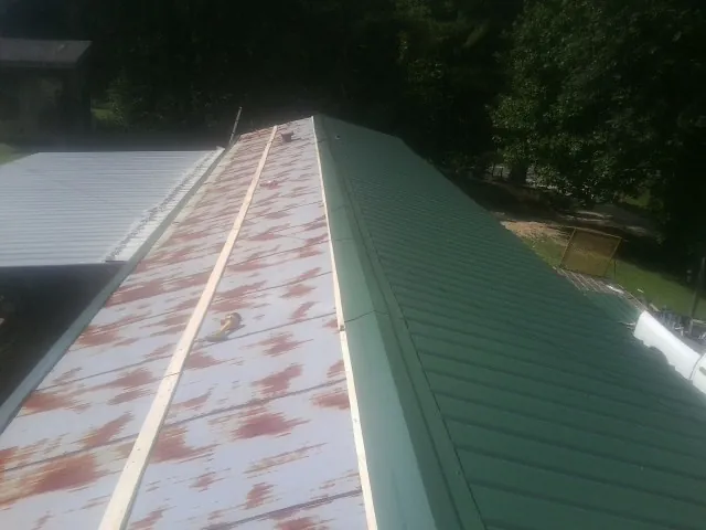 Old rusted panels beside newly installed green metal roofing — Wind Damage Roof Repair by Roofing Brothers in Trimble