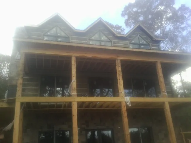 Dormers and porch framing on a large log home under construction — Roof Coating work by our crew in Trimble