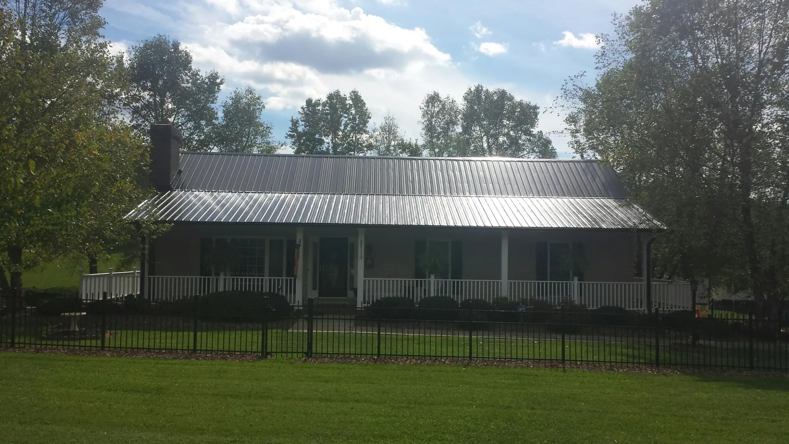 Gray metal roof on a brick ranch with a full width front porch — Gutter Guard Installation work by our crew in Trimble